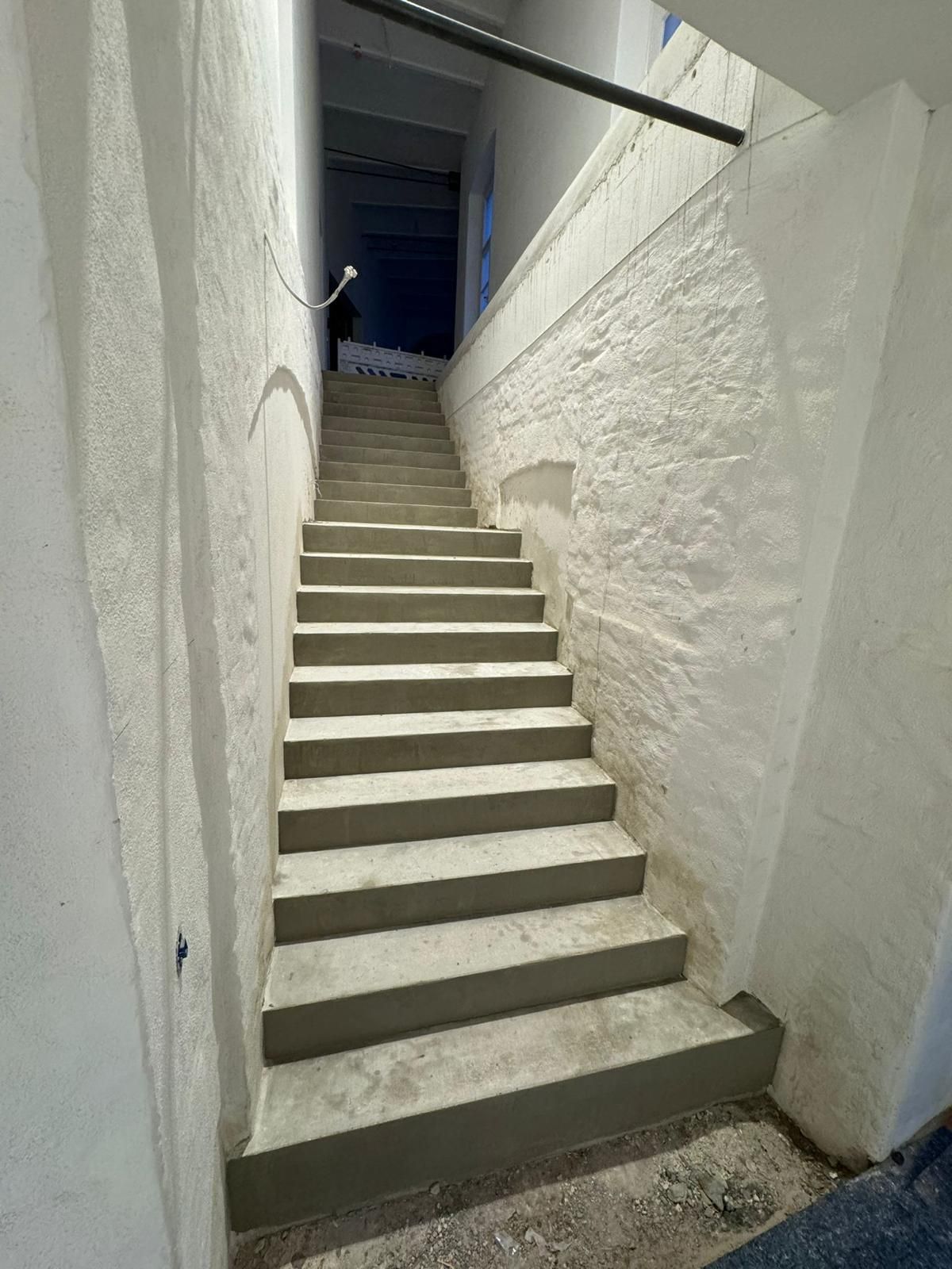Neue Stahlbetontreppe zwischen weiß gestrichenen Wänden